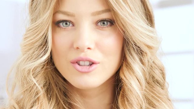 blonde woman doing shh with finger on her lips and then smiling