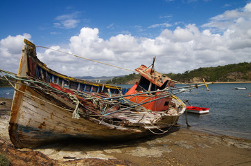 Fishing boat wrecked into a rocky river bank