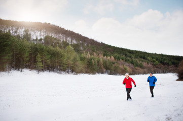 Senior couple jogging in winter nature.