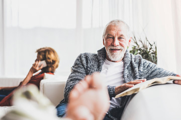 Senior couple with smartphone relaxing at home.