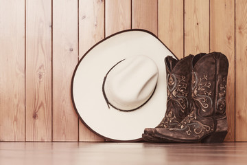cowgirl embroidered boots and white hat on wooden background - text space