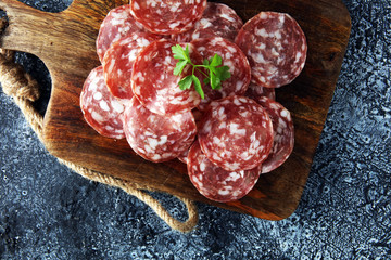 thinly sliced salami on a wooden texture on the background.