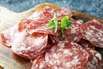 thinly sliced salami on a wooden texture on the background.