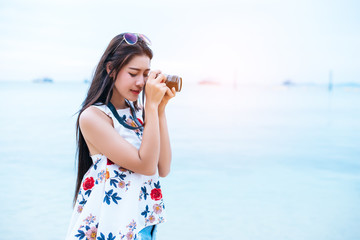 Asian woman enjoy take photo by digital camera at beach. Single and lonely woman concept. Happiness and Lifestyle concept. Beauty and Nature theme. Ocean and sea background. Technology and woman day