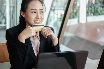 woman holding a credit card and using computer for online shopping at cafe. businesswoman purchase goods from internet at office. female startup make payment on bank website at workplace
