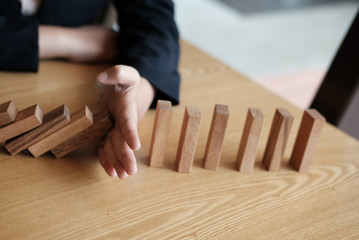 hand stopping effect of domino continuous toppled. busineeman protecting falling wood block....