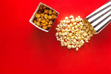 Popcorn in paper bag scattered on red background top view copy space