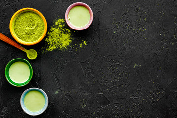 Brew matcha tea. Bowl with powder and cups with beverage on black background top view copy space