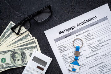 Housing loan. Draw up a mortgage. Mortgage application near keychain in shape of house and money on black background top view