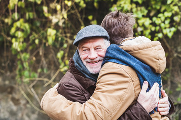 Senior father and his young son on a walk, hugging.