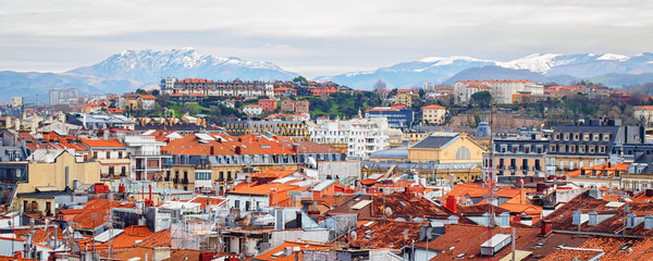 Naklejka na ściany i meble Panorama of San Sebastian (Donostia) in cloudy winter day with the snowy mountains on horizon.