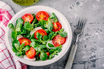 healthy green salad bowl with tomato and mozzarella on rustic background