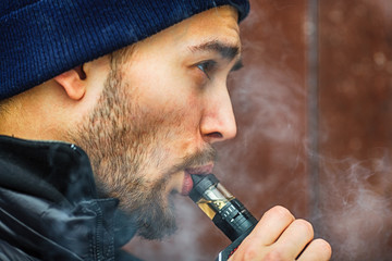 Vape man. Portrait of a handsome young white guy vaping an electronic cigarette opposite the...