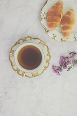 Breakfast table with cup of tea and croissant