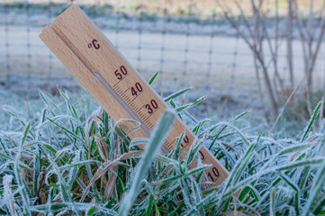 Stehender Holz Thermometer im Gras mit Eis