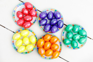 Easter eggs on wooden background. Colorful eggs in different colors - red, yellow, orange, purple and green.