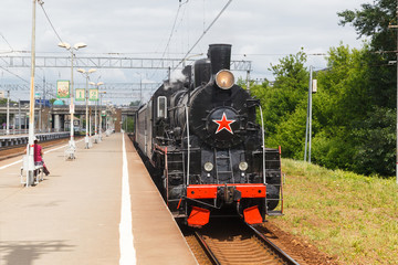 old black steam locomotive in Russia at the summer on a background of blue sky