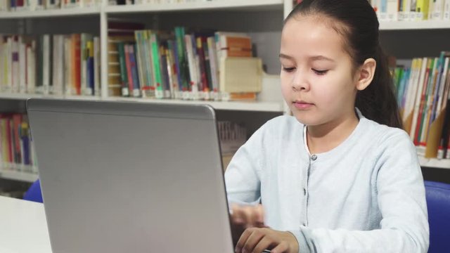 Pretty little Asian girl studying working on her laptop