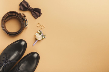 Closeup of bow-tie, belt, shoes, floral corsage, golden rings.
