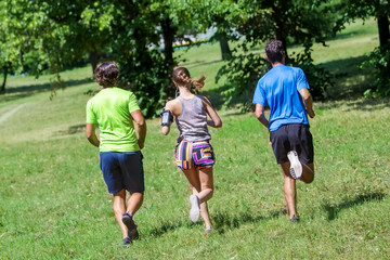 Obraz na płótnie Canvas Woman and two young men running in the park