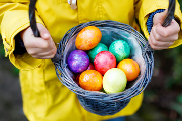Close-up of hands of little child with colorful Easter eggs in basket