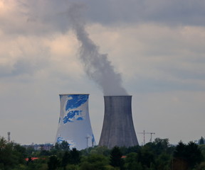 Dwa duże kominy, z jednego unosi się bury gęsty dym, pochmurne niebo, na dole zieleń © Wioletta