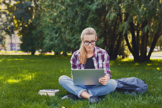 Happy young woman using laptop in park