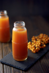 Sea buckthorn juice in a jar on a dark wooden background.