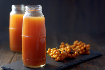 Sea buckthorn juice in a jar on a dark wooden background.