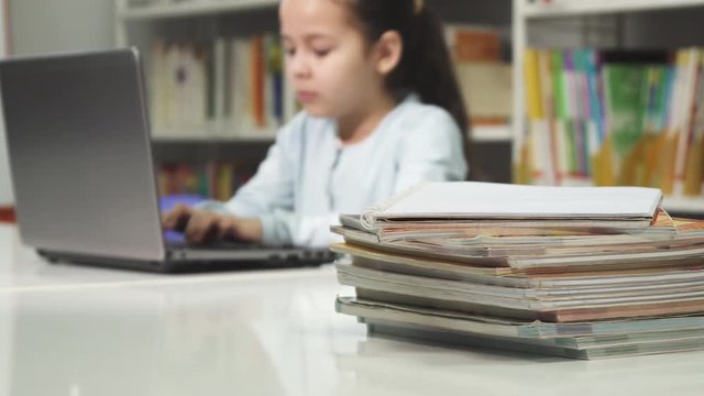 Little girl using laptop at school studying doing homework