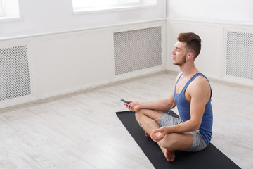 Man training yoga in lotus pose, copy space