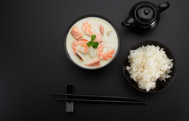 Tom kha soup with seafoods over dark background.