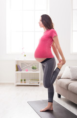 Pregnant woman stretching legs training indoors