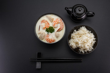 Tom kha soup with seafoods over dark background.