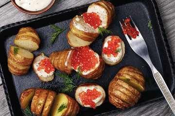 Baked potatoes with Dutch sauce and red caviar on a tray, top view