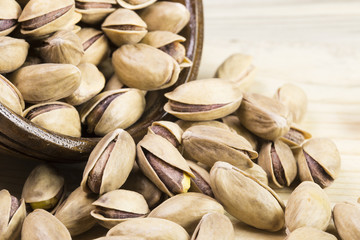 wooden bowl of pistachios on wooden background 