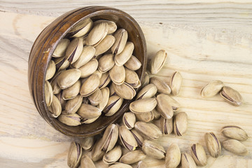 wooden bowl of pistachios on wooden background 