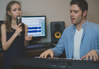 Man with little girl rehearsing song in music studio.