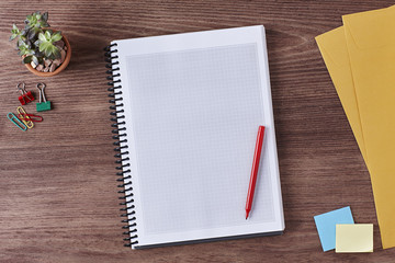 Office Workspace. Top View of a Business Workplace. Wooden Desk Table, Pen, Pencil, a Blank Notebook, Envelope, Plant Pot, Clips. Copy space for text or Image