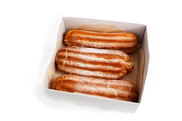Three eclairs in a paper box. Isolate on a white.