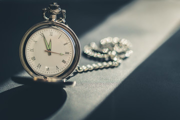 Vintage pocket watch on chain on a dark background