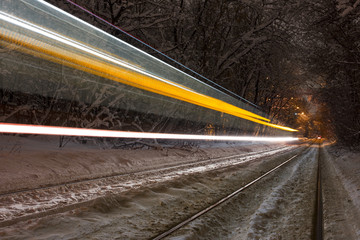 Tram riding fast in the forest at night