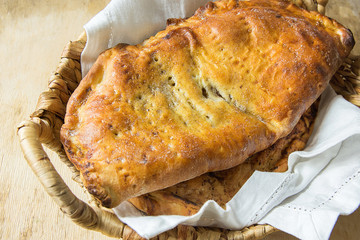 Scrumptious Home Baked Italian Pastry Calzone with Sweet Apple Pie Raisins Cinnamon Filling in Wicker Basket on White Linen Napkin. Aged Wood Table. Rustic Kitchen Interior. Cozy Atmosphere