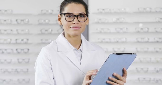 An ophthalmologist while using the ipad, turns around looks at the camera and smiles. Concept of: technology, application for ophthalmologists, medical examinations.