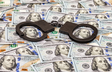 Steel black handcuffs lying on the background of american dollars
