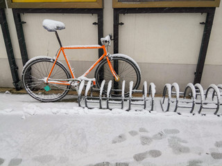 Fototapeta na wymiar Orange bike locked to a rack. Covered with snow and ice.
