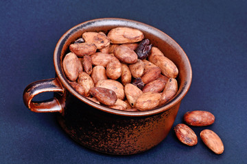 Cocoa beans in a cup on blue background