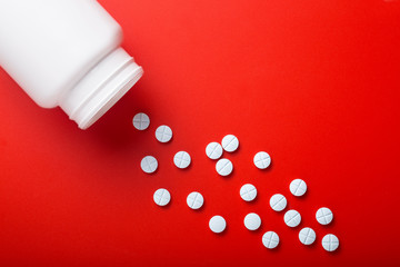 Medical pills spilling out of bottle. On red background. Top view . Medicine concept