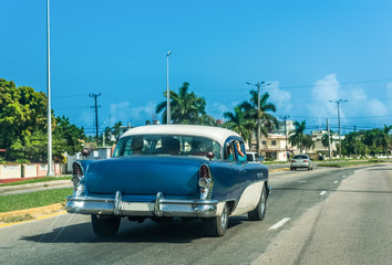 Obraz na płótnie Canvas Blauer amerikanischer Oldtimer mit weissem Dach fährt durch Varadero Kuba - Serie Kuba Reportage