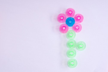 Multicolored plastic bobbin for sewing machine. in shape of a flower in .white background